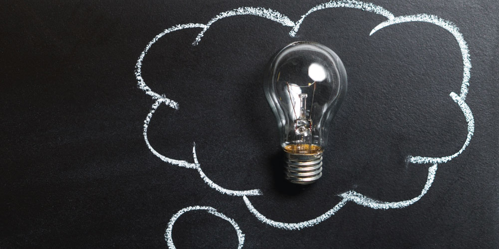 A light bulb on a blackboard with a thought cloud drawn around it