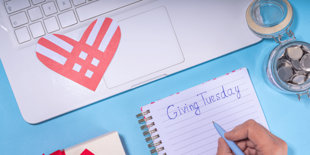 person writes Giving Tuesday on a notebook
