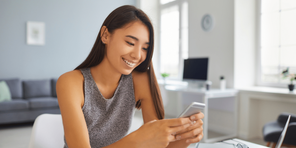 smiling woman looks at her phone