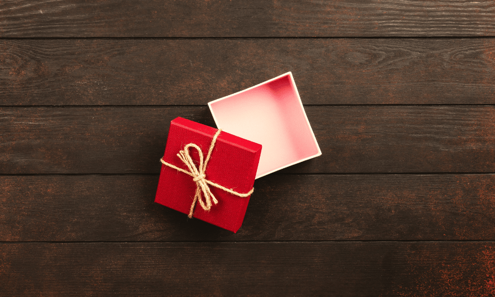 A small red gift box sits open and empty on a wooden table.